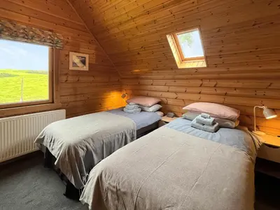 a bedroom with two beds in a log cabin at Bengairn in Ringford