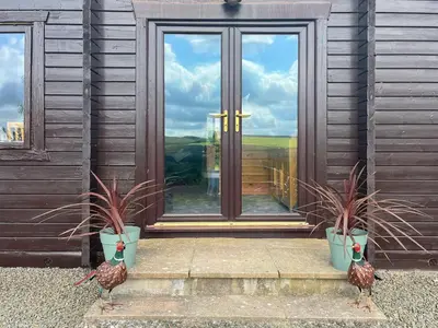 two peacocks standing in front of a house with a door at Bengairn in Ringford