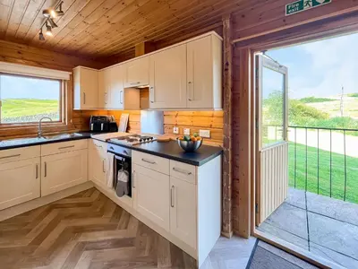 a kitchen with white cabinets and a large window at Bengairn in Ringford