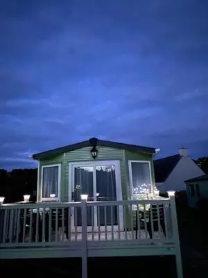 a small green house with a white railing at Rosie in Whithorn