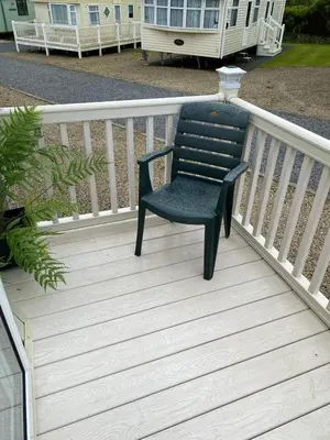 a black chair sitting on a wooden deck at Rosie in Whithorn