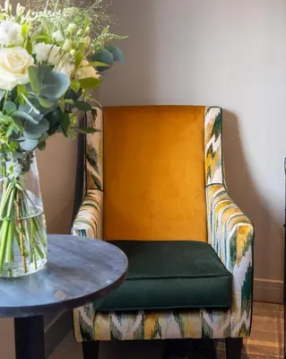 a chair with a table and a vase with flowers at DeiRa Hotel & Apartments in Prestwick