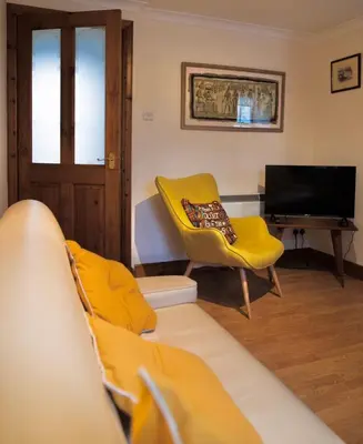 a living room with a yellow couch and a television at No5 The Smiddy in Wigtown