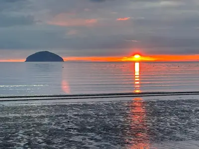 a sunset on the beach with the sun reflecting in the water at Peel House Bed and Breakfast in Girvan