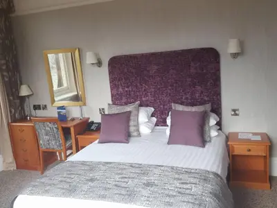 a bedroom with a large bed with a purple headboard at Keswick Country House Hotel in Keswick