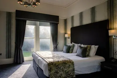 a bedroom with a large bed and a large window at Keswick Country House Hotel in Keswick