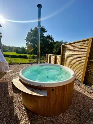 a jacuzzi tub with a fountain in a yard at Lintmill Lodges - Thistle Shepherds Hut in Sorn
