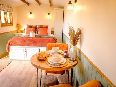 a small room with a bed and a table with chairs at Lintmill Lodges - Heather Shepherds Hut in Sorn