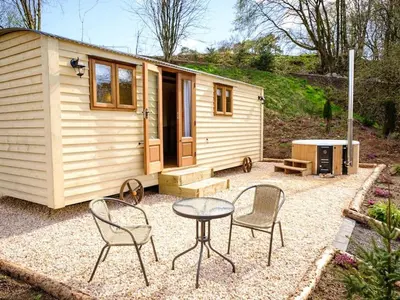 a small cabin with chairs and a table in front of it at Lintmill Lodges - Heather Shepherds Hut in Sorn