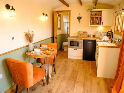 a kitchen with a small table and a kitchen with a sink at Lintmill Lodges - Heather Shepherds Hut in Sorn