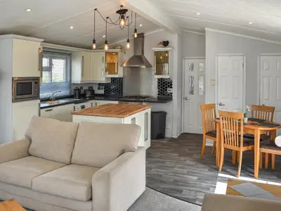 a living room with a couch and a table in a kitchen at Meadows Lodge - Uk46825 in Plumbland