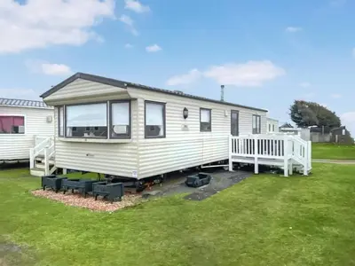 a white tiny house on a grass field at Merse Place 57- Uk46905 in Mainsriddle