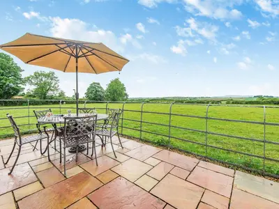 a table and chairs with an umbrella on a patio at Stackgarth in Gilcrux