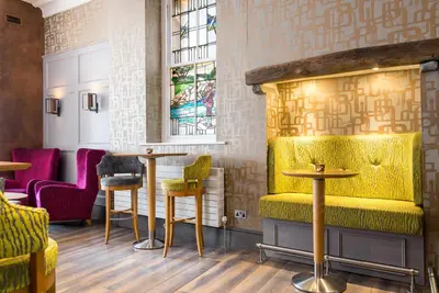 a restaurant with yellow seating and tables and chairs at Inn on the Square in Keswick