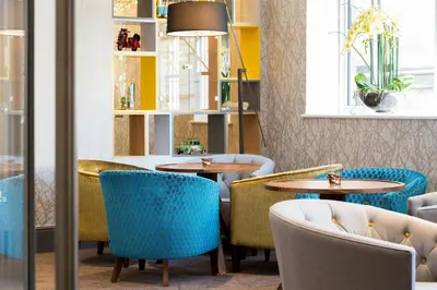 a restaurant with round tables and blue chairs at Inn on the Square in Keswick