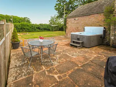 a patio with a table and a hot tub at The Bothy in Ivegill