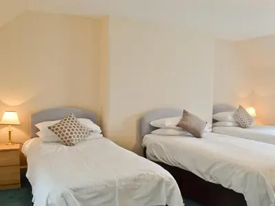a bedroom with two beds with white sheets and pillows at Park Cottage in Gatehouse of Fleet