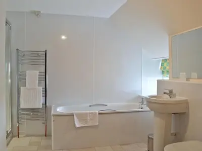 a white bathroom with a tub and a sink at Park Cottage in Gatehouse of Fleet