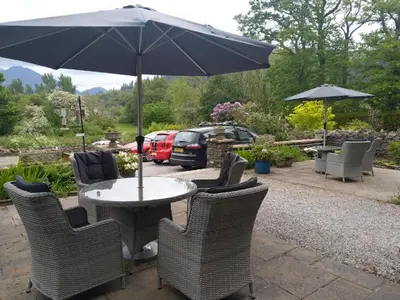 a table with chairs and an umbrella on a patio at Lakeside Country Guest House in Bassenthwaite Lake
