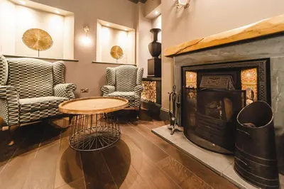 a living room with a table and a fireplace at Borrowdale Gates Hotel in Keswick