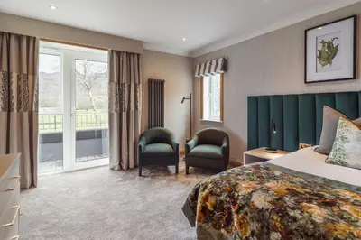 a hotel room with a bed and two chairs at Borrowdale Gates Hotel in Keswick