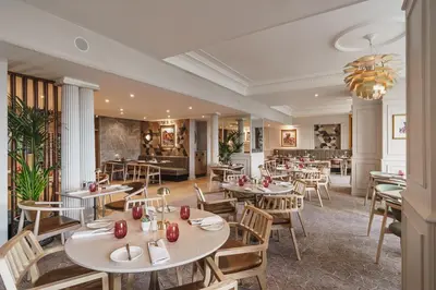 a restaurant with tables and chairs and a chandelier at Lodore Falls Hotel & Spa in Keswick