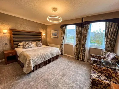 a bedroom with a bed and a chair in it at Lodore Falls Hotel & Spa in Keswick