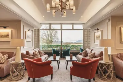 a living room with couches and chairs and a large window at Lodore Falls Hotel & Spa in Keswick