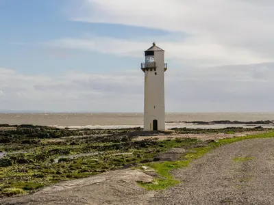 a lighthouse on the beach with a gravel road at Seascape in Mainsriddle