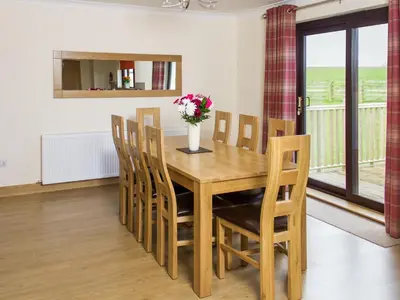 a dining room table with chairs and a vase of flowers at Seascape in Mainsriddle