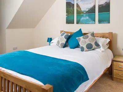 a bedroom with a large bed with blue sheets and pillows at Seascape in Mainsriddle