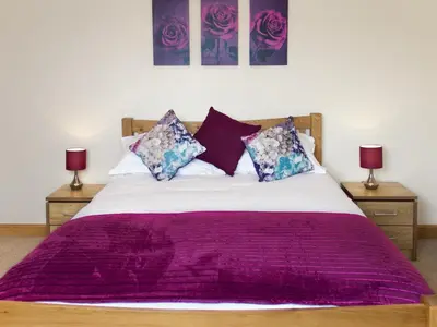 a bedroom with a bed with purple sheets and two lamps at Seascape in Mainsriddle