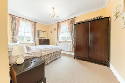 a bedroom with a bed and a dresser and windows at Stickle Tarn in Keswick