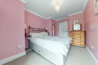 a pink bedroom with a large bed and a dresser at Stickle Tarn in Keswick