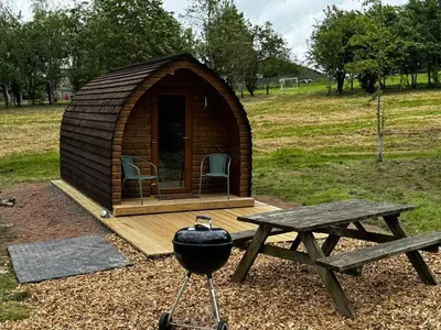 a wooden cabin with a picnic table and a grill at Howbeck Lodge in Hesket Newmarket