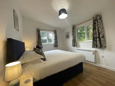 a bedroom with a large bed and two windows at Swallows Lodge in Keswick