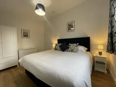 a bedroom with a large bed with white sheets at Swallows Lodge in Keswick