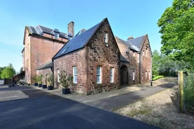 an old brick building with a black roof at 20 The Courtyard, Ballochmyle House in Mauchline