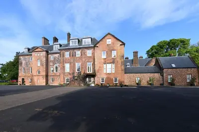 a large red brick building with a black roof at 20 The Courtyard, Ballochmyle House in Mauchline
