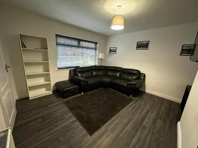 a living room with a leather couch and a window at Large 3 bed property in Whitehaven