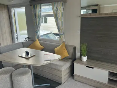 a living room with a table and a couch at Robinson retreats beautiful caravan with sea views pet friendly in Mainsriddle