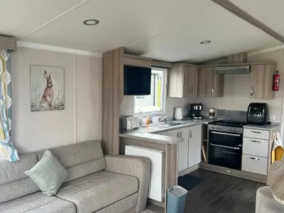 a living room with a couch and a kitchen at Robinson retreats beautiful caravan with sea views pet friendly in Mainsriddle