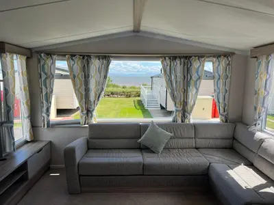 a living room with a couch and a large window at Robinson retreats beautiful caravan with sea views pet friendly in Mainsriddle