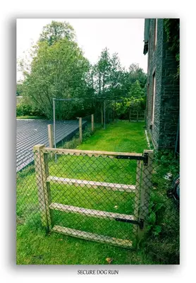 a chain link fence with a gate in a yard at Clarefoot Cottage in Moffat