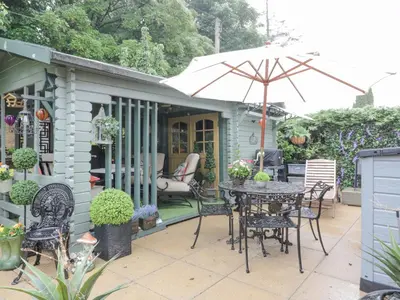 a patio with a table and chairs and an umbrella at Scotia At The Pow in Annan