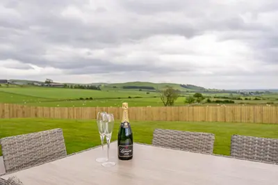 a bottle of wine and a glass on a table at Berryrigg Cottage in Dumfries