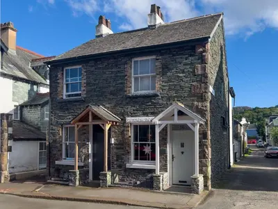 an old stone house with a white door at Anley Cottage with garden and private parking in Keswick in Keswick