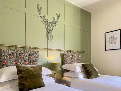 a bedroom with two beds and a deer head on the wall at Anley Cottage with garden and private parking in Keswick in Keswick