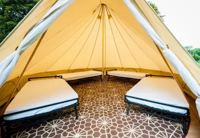 two beds in a tent with a tiled floor at Nine Yards Bell Tents at the TT - Douglas in Douglas