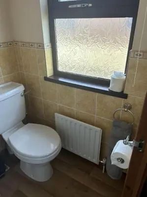 a bathroom with a white toilet and a window at Livingstones Lodge, Lake District in Plumbland